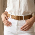 Person wearing a white shirt and white pants with a brown belt.