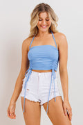 Woman wearing a blue halter top and white shorts on a plain background