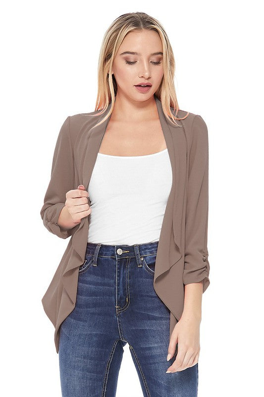 Woman wearing a brown cardigan over a white top and blue jeans on a white background