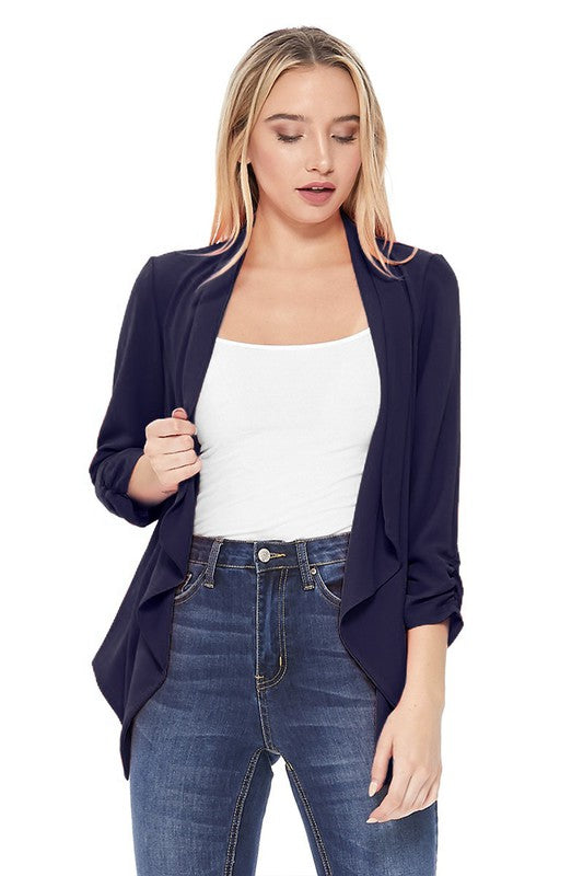 Woman wearing a navy blue cardigan over a white top and blue jeans on a white background