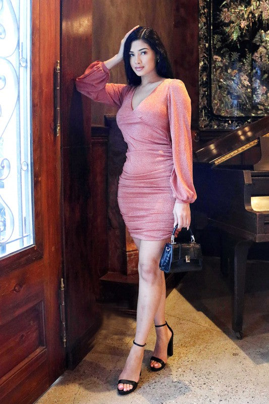 Woman in a pink dress standing in a room with wooden paneling and a piano.