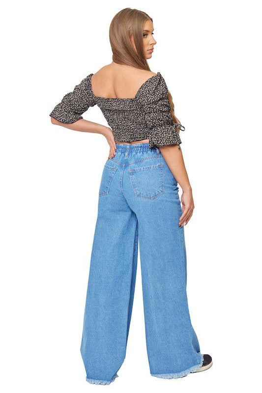 Woman wearing a patterned top and blue jeans on a white background