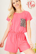 Woman wearing a pink romper with a leopard print pocket on a light background