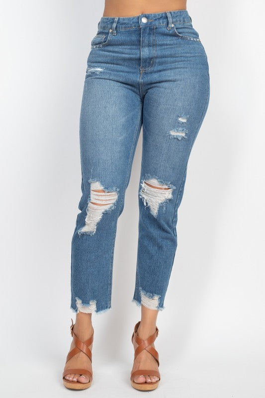 Distressed blue jeans worn by a person on a white background