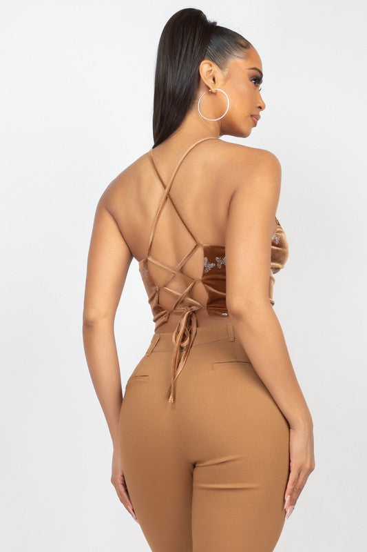 Woman wearing a brown jumpsuit with criss-cross straps on a white background