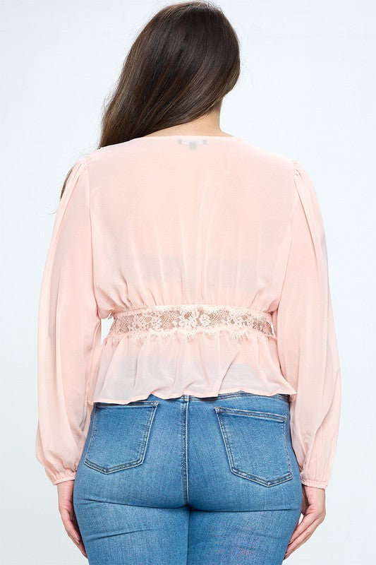 Person wearing a light pink blouse with a belt and blue jeans on a white background