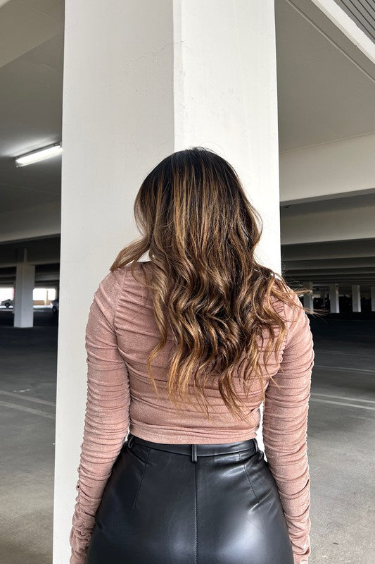 Person wearing a pink top and black leather skirt standing in an indoor parking garage.