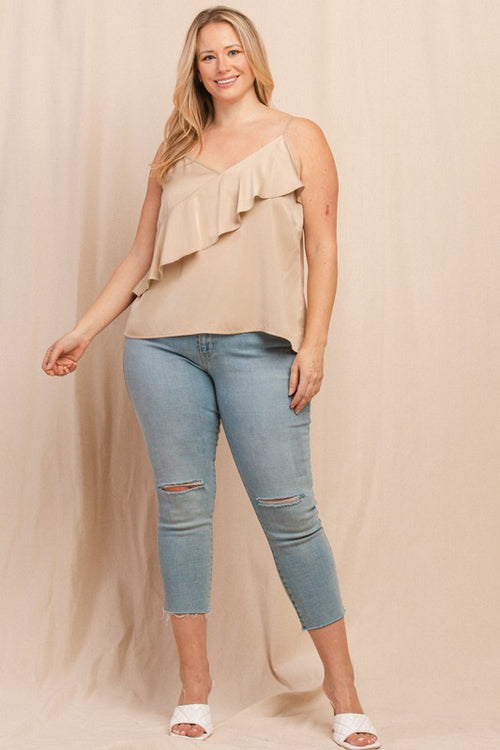 Woman wearing a beige top and light blue jeans against a beige background