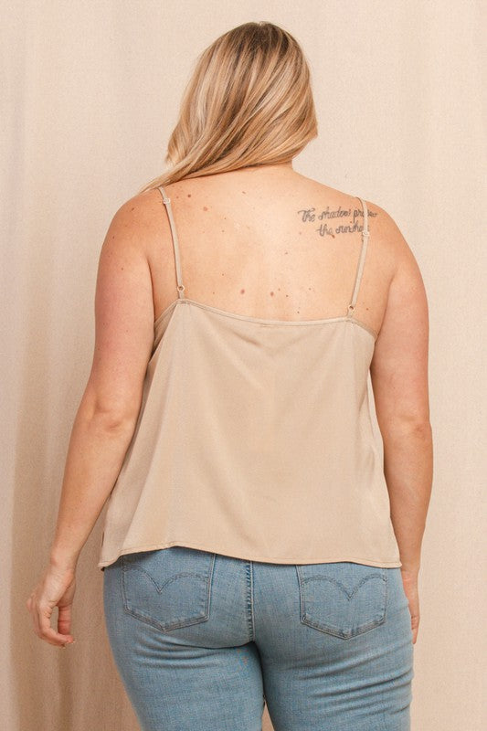 Person wearing a beige tank top and blue jeans against a beige background