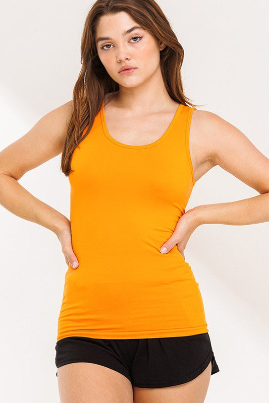 Woman wearing an orange tank top and black shorts on a white background