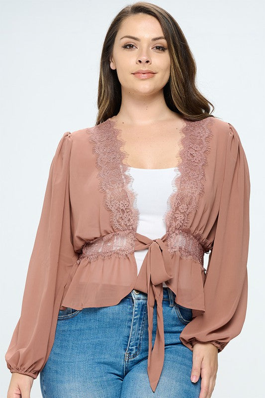 Woman wearing a brown lace-trimmed top with a white shirt and blue jeans on a light gray background