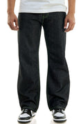 Men’s dark wash straight-leg jeans with green contrast stitching, worn with a white t-shirt and black-and-white sneakers on a neutral background.