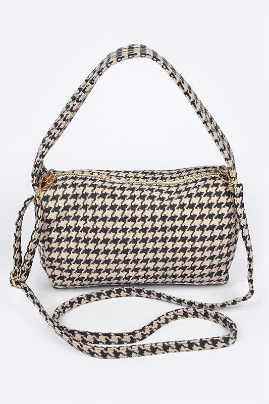 Houndstooth patterned handbag with a strap on a white background