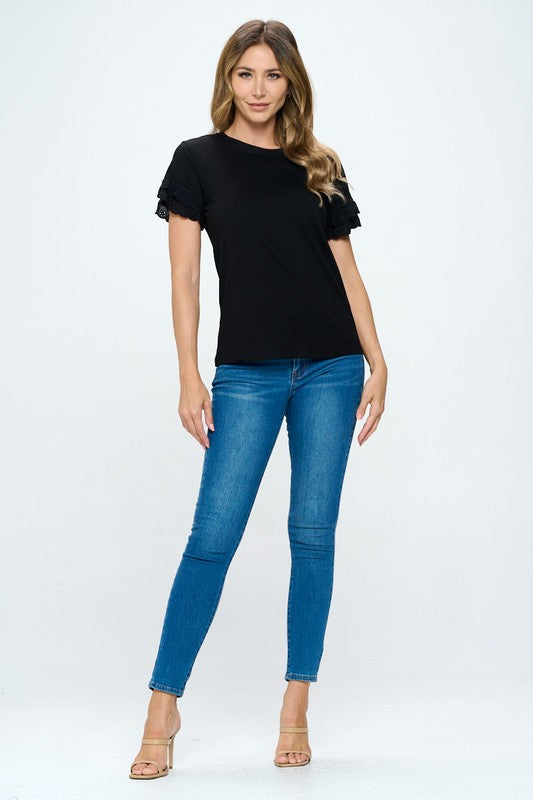Woman wearing a black top and blue jeans on a white background
