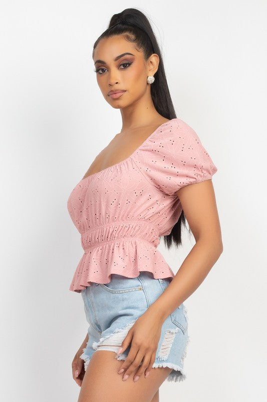 Woman wearing a pink one-shoulder top and denim shorts on a white background