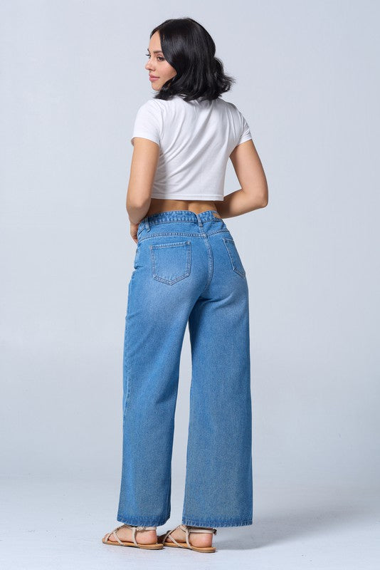 Woman wearing blue jeans and a white top on a plain background