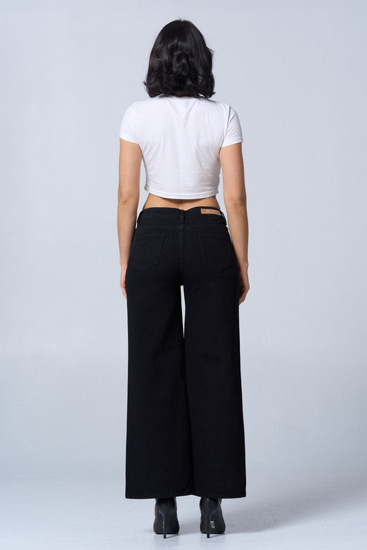 Person wearing a white crop top and black wide-leg pants on a light gray background
