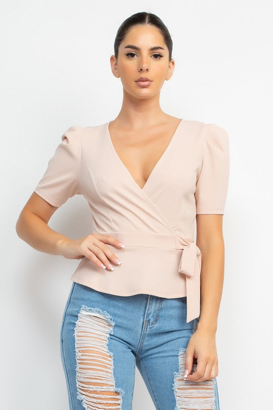 Woman wearing a beige top and blue jeans with a white background