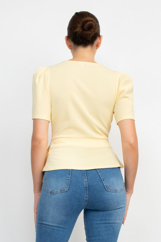 Person wearing a light yellow top and blue jeans against a white background