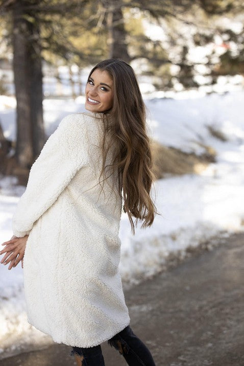 Woman in a white coat standing in a snowy landscape