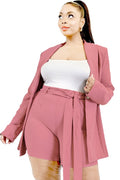 Woman wearing a pink blazer and shorts set on a white background