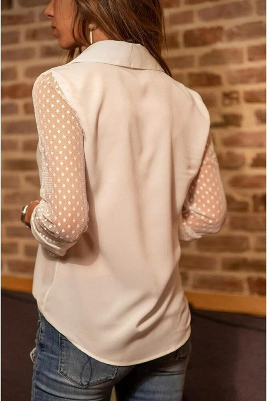 Woman turned away wearing a white blouse with sheer sleeves. 