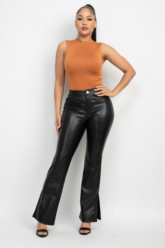 Woman wearing a brown sleeveless top and black leather pants on a white background