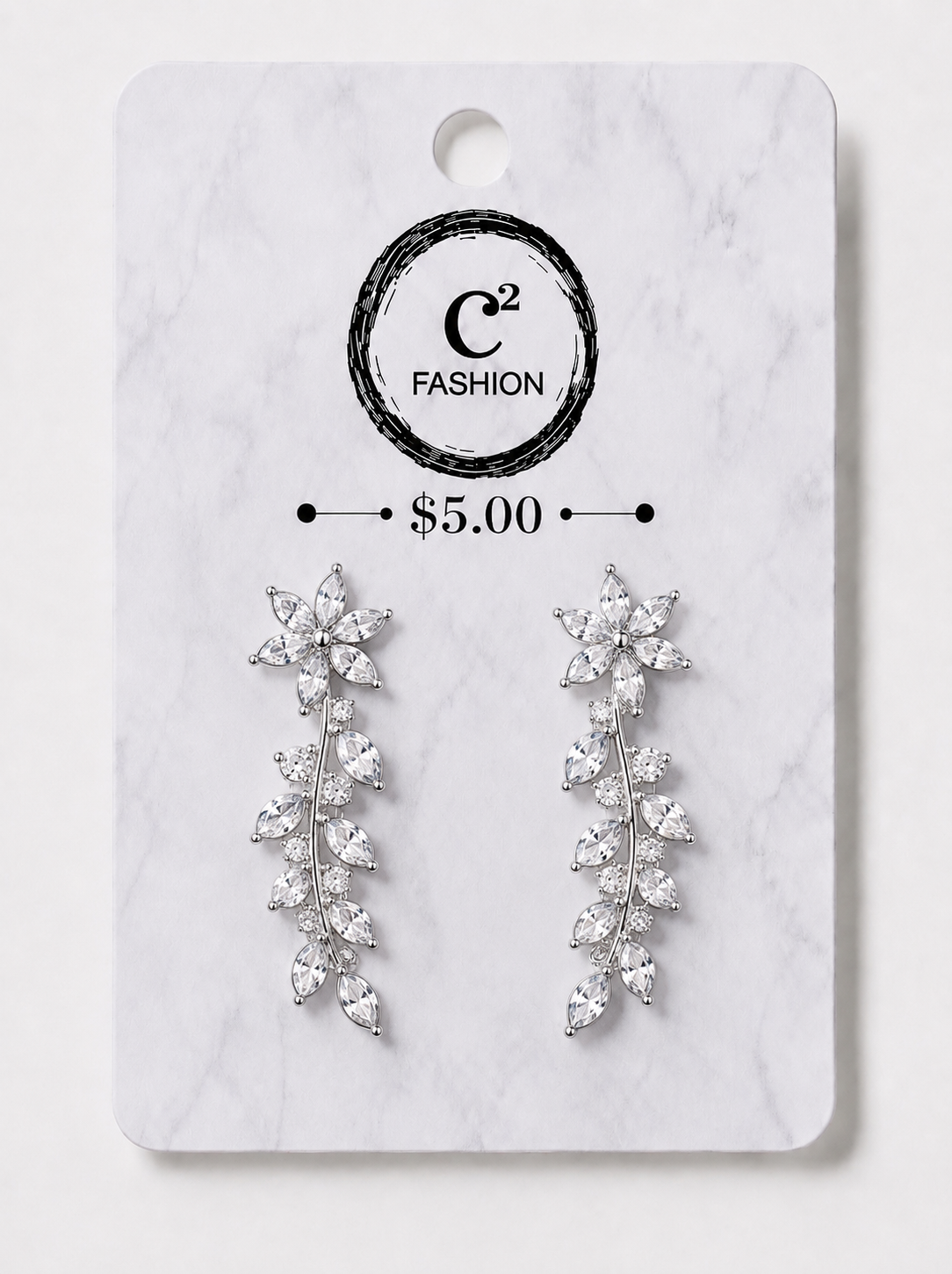 A pair of silver-toned dangle earrings with clear crystal-like leaves, displayed on a white marble-style retail card with the C² FASHION logo and a $5.00 price mark.
