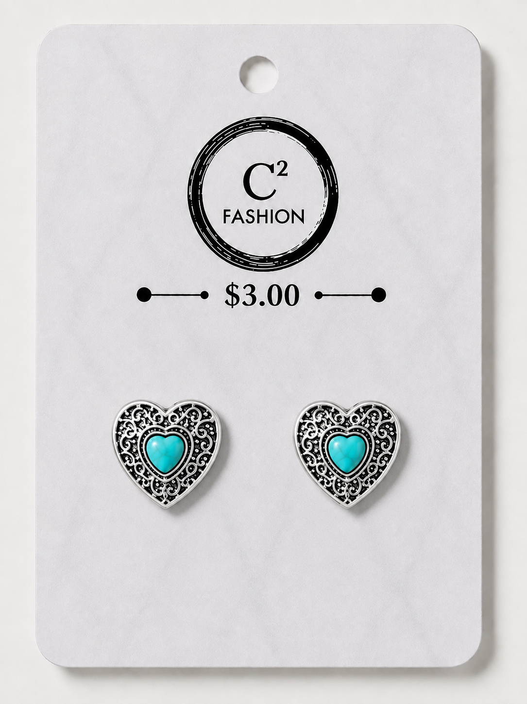 A pair of heart-shaped stud earrings with silver filigree borders and turquoise centers, mounted on a white display card printed with the brand name 'C2 FASHION' and a price of '$3.00'.