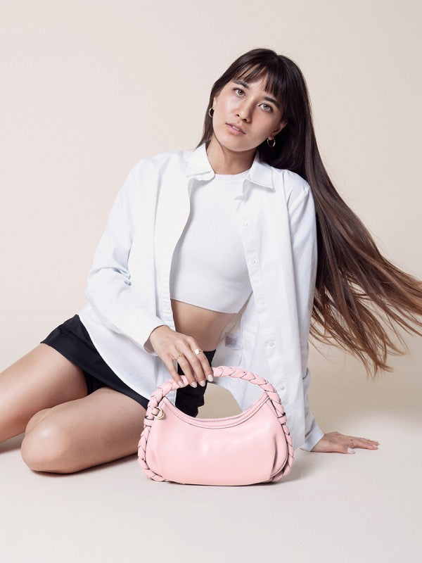 Woman holding a pink handbag against a plain background