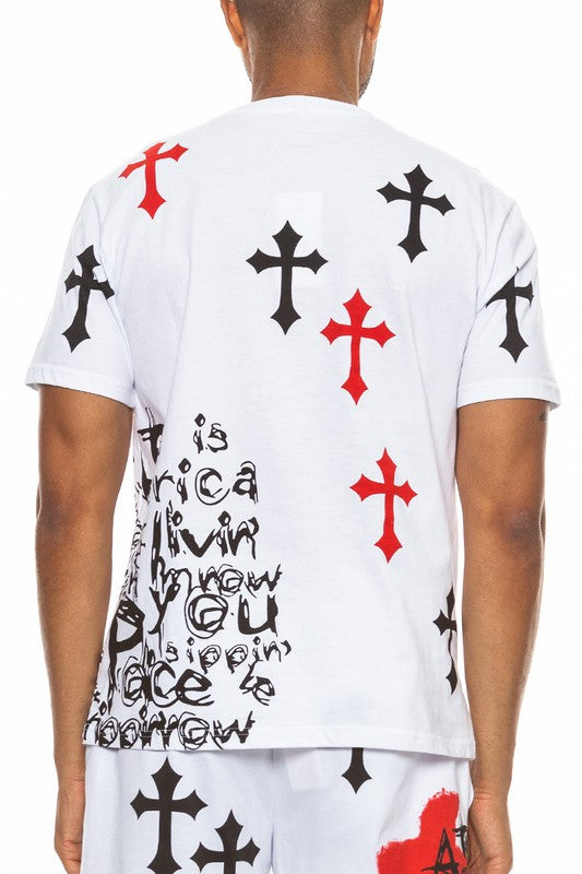 Person wearing a white t-shirt with black and red cross designs and text.
