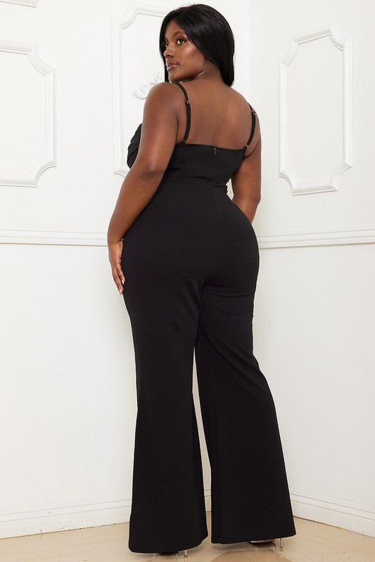 Woman wearing a black jumpsuit against a white wall