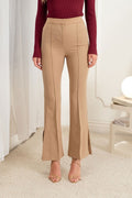 Person wearing beige flared pants and a red top in a room with white walls and a lamp.