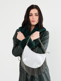 Woman holding a silver handbag with fringe details on a white background