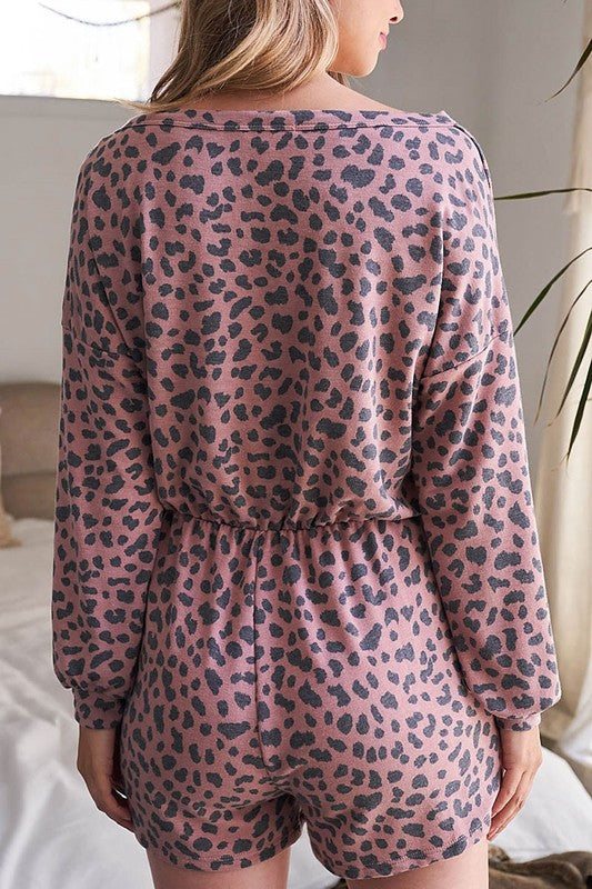 Person wearing a pink leopard print romper in a neutral setting