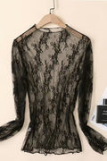 Black lace top on a hanger against a beige background