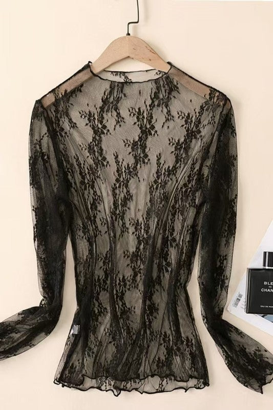Black lace top on a hanger against a beige background