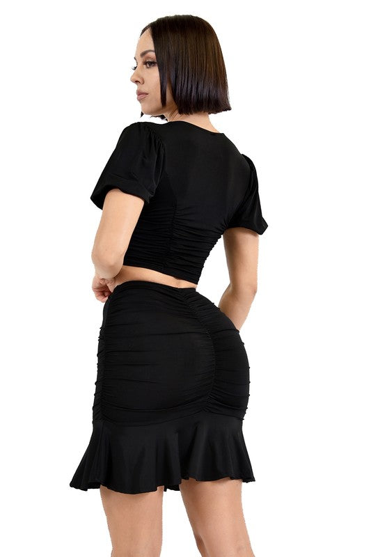 Woman wearing a black outfit with a skirt on a white background
