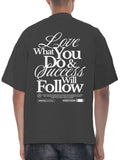 Black t-shirt with motivational quote on the back, worn by a person.