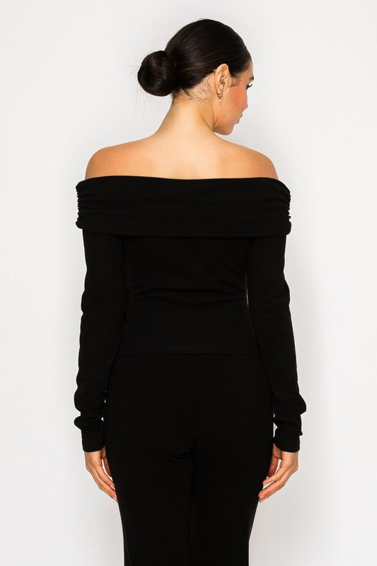 Woman wearing a black off-shoulder top against a white background