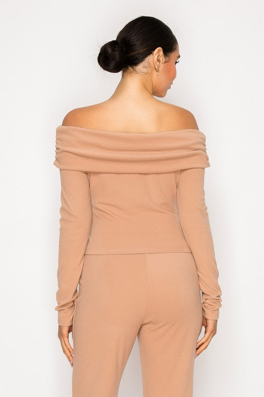 Woman wearing a beige off-shoulder jumpsuit on a white background