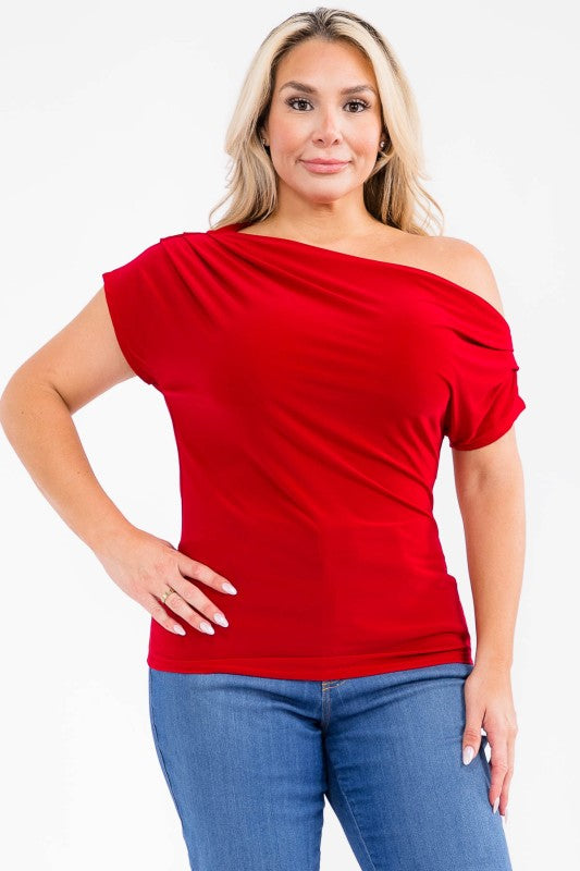 A woman modeling a bright red off-the-shoulder short-sleeve top with blue jeans, photographed against a plain white studio background.
