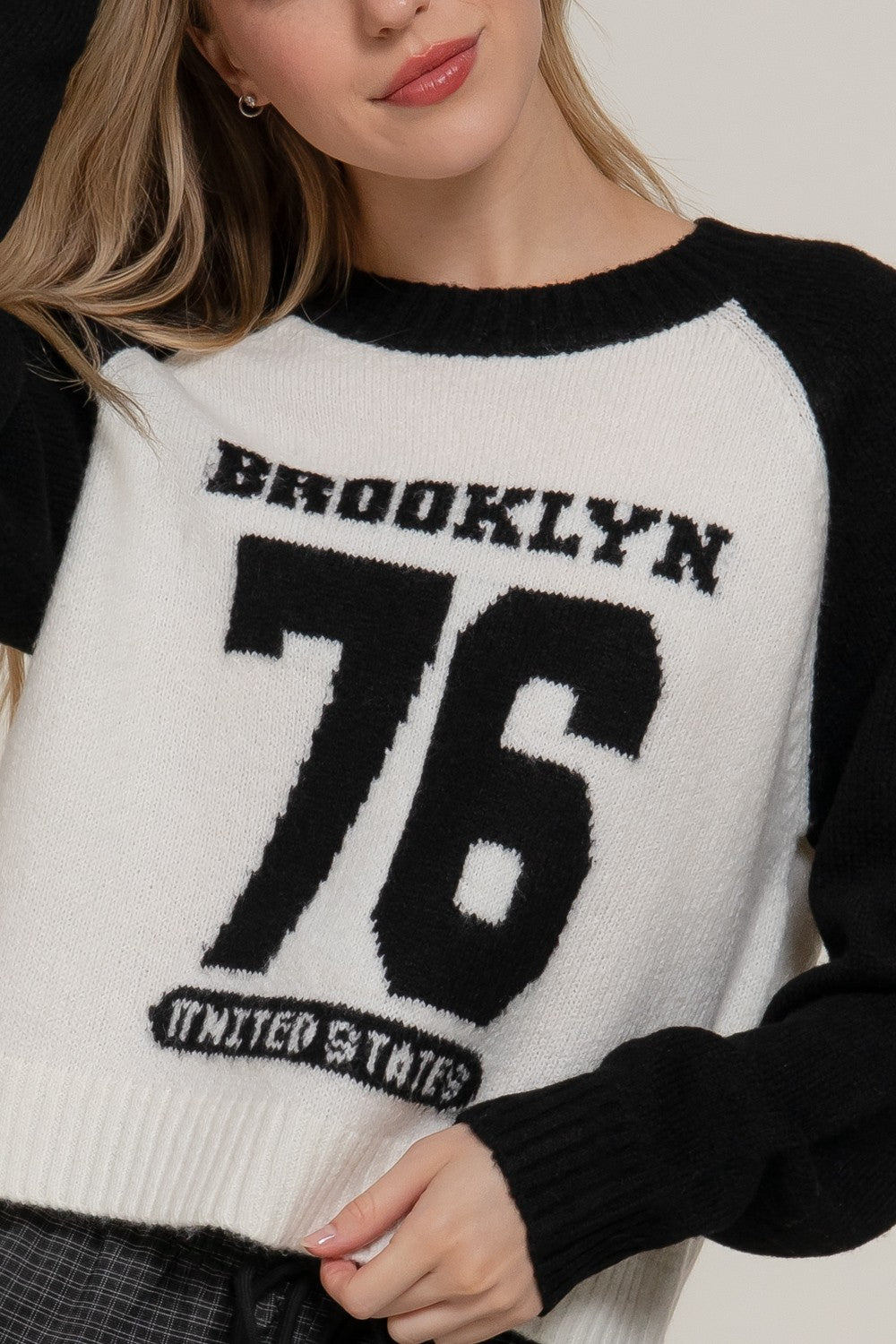 Close-up of a black-and-white knit sweater featuring “Brooklyn 76 United States” lettering and a bold number 76 graphic.