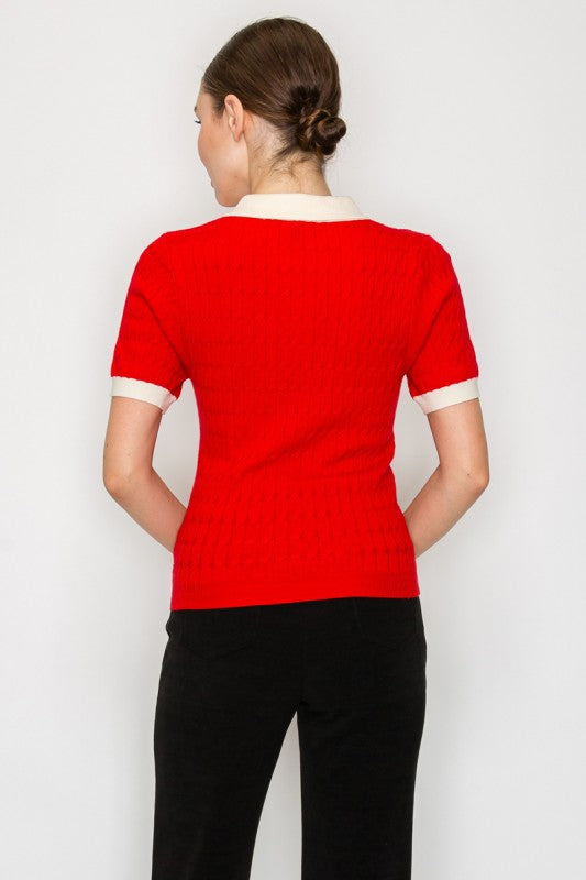 Person wearing a red top with white trim on a plain background