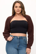 Woman wearing a brown cardigan, black tube top, and blue jeans on a white background