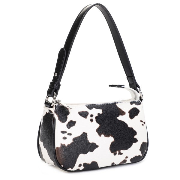 Handbag with cow print pattern on a white background with black handle. 