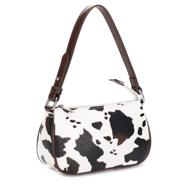 Handbag with cow print pattern on a white background with brown handle. 
