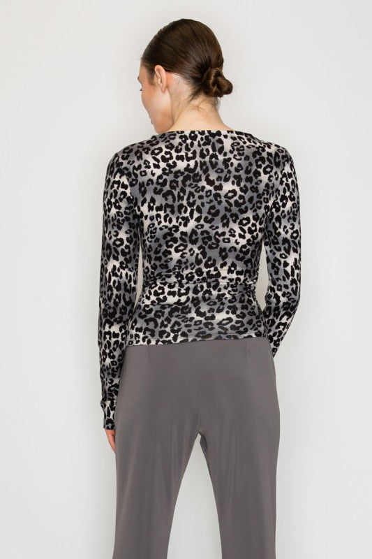 Person wearing a leopard print top and gray pants on a white background