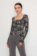 Woman wearing a leopard print top and gray pants against a white background