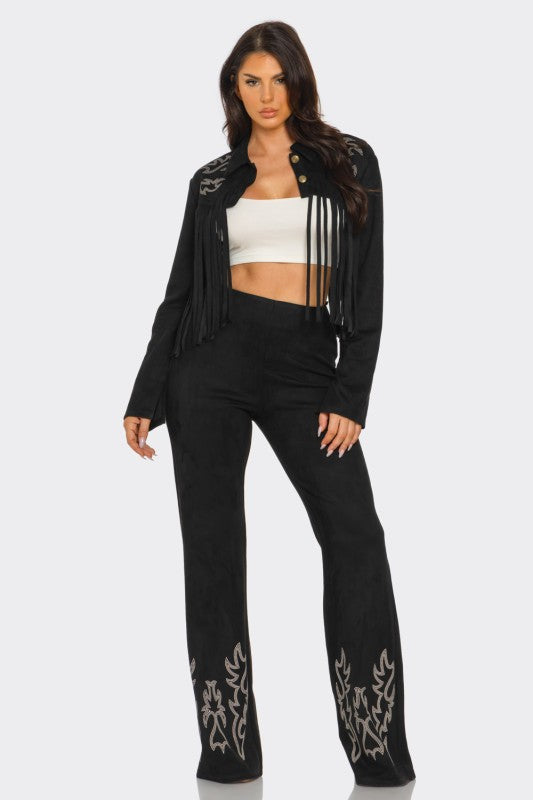 Woman wearing a black fringe jacket and black pants with white patterns on a white background